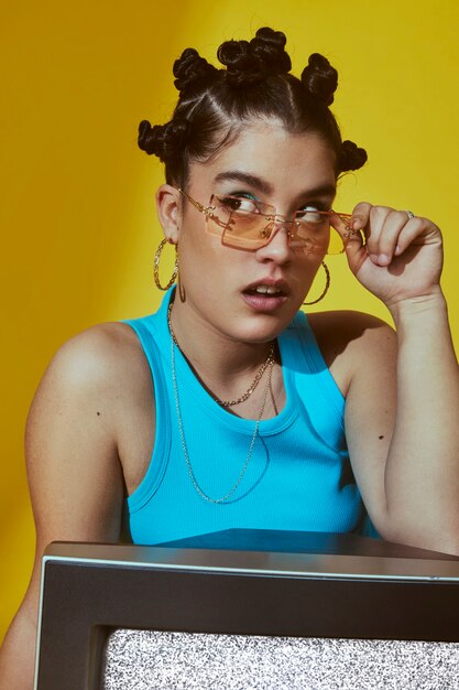 Retrato de mujer joven en estilo de moda de 2000 posando con tv