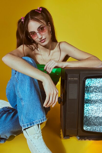Retrato de mujer joven con estilo de moda de los años 2000 posando con tv