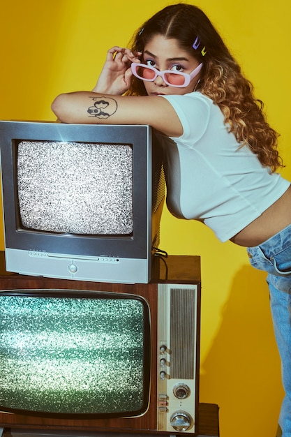 Retrato de mujer joven con estilo de moda de los años 2000 posando con tv