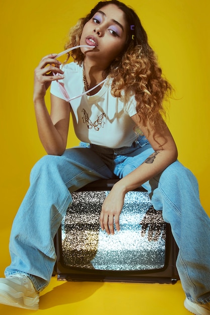 Retrato de mujer joven con estilo de moda de los años 2000 posando con tv