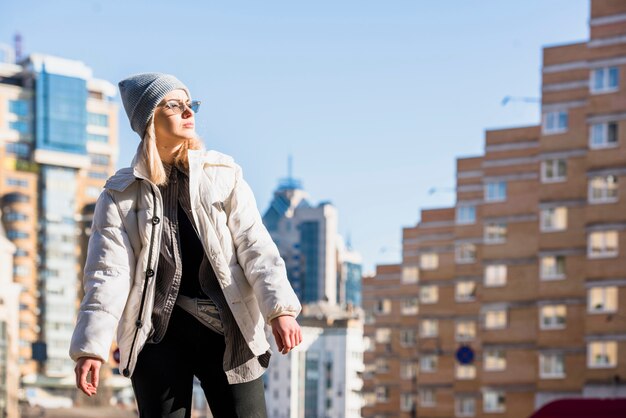 Retrato de mujer joven con estilo de pie delante de los edificios