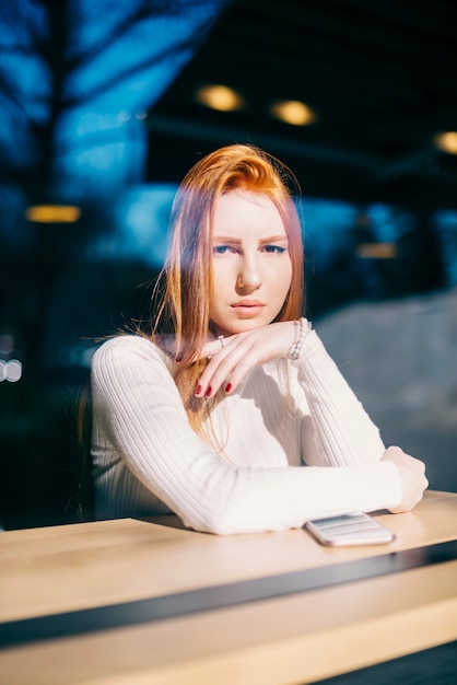 Retrato de una mujer joven con estilo que se sienta en café