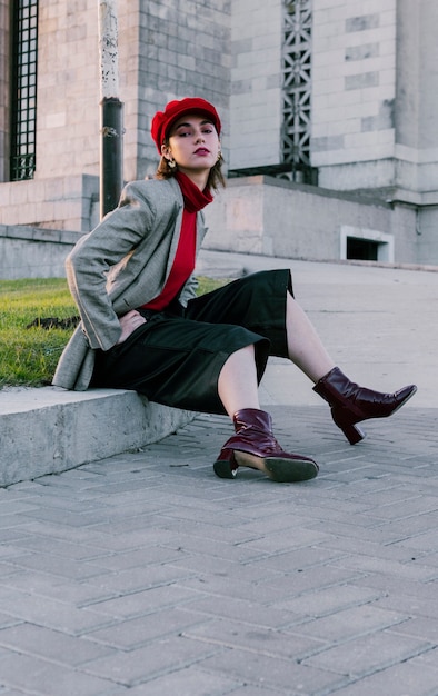 Retrato de una mujer joven con estilo que se sienta cerca de la hierba verde