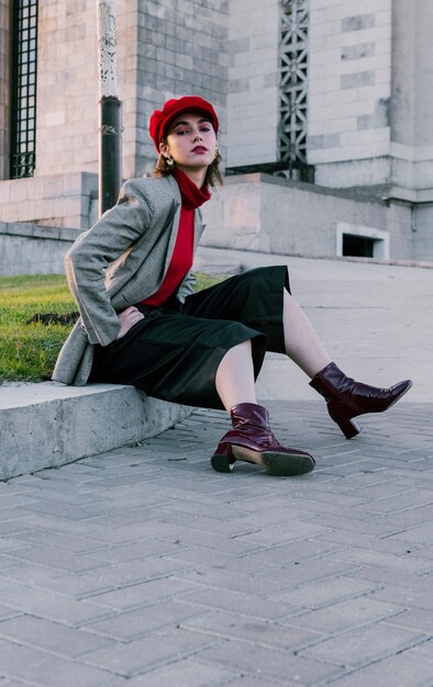 Retrato de una mujer joven con estilo que se sienta cerca de la hierba verde