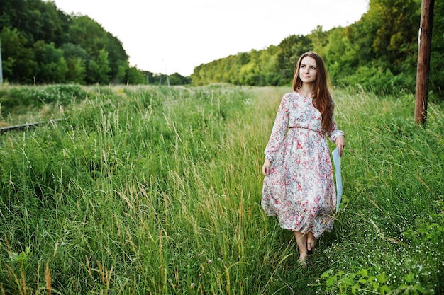 Foto gratuita retrato de una mujer joven fabulosa en vestido caminando en la hierba alta