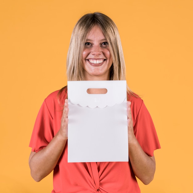 Foto gratuita retrato de mujer joven feliz con bolsa de papel blanco