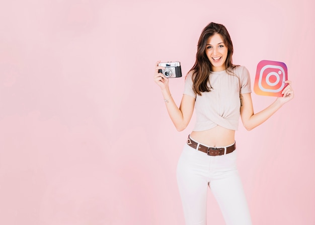 Foto gratuita retrato de una mujer joven feliz con cámara e icono de instagram