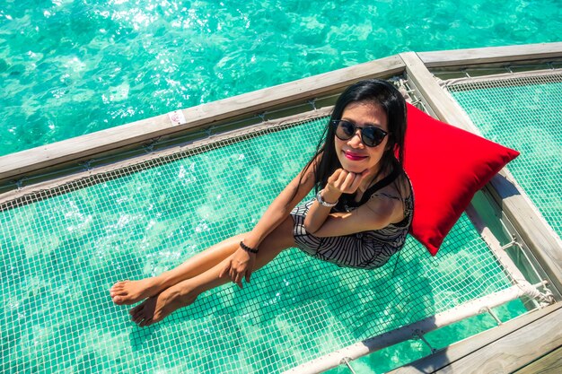 Retrato de mujer joven feliz en la hermosa villa de agua en la isla de Maldivas. Viajes y vacaciones. Tiro al aire libre