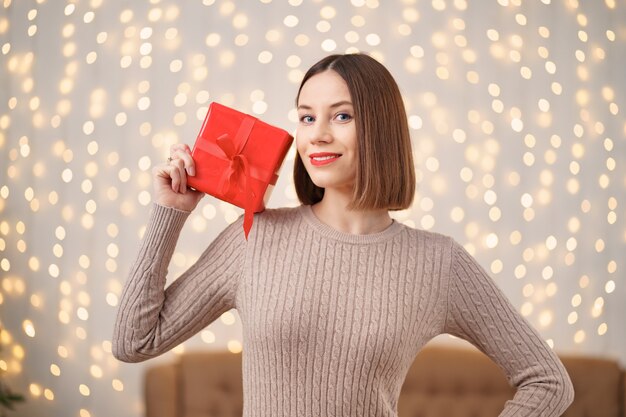 Retrato de mujer joven feliz con labios rojos con caja de regalo envuelta.