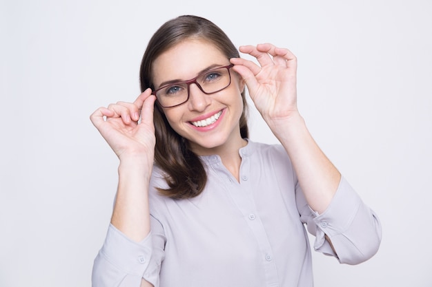 Retrato de mujer joven feliz que intenta en las lentes