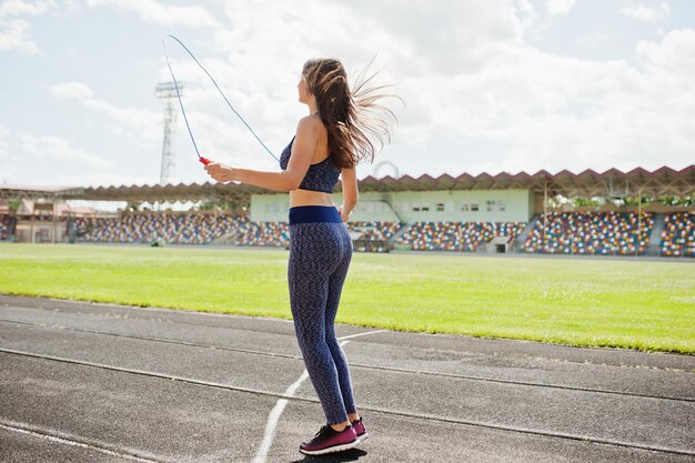 Retrato de una mujer joven feliz en ropa deportiva haciendo ejercicios con cuerda de saltar