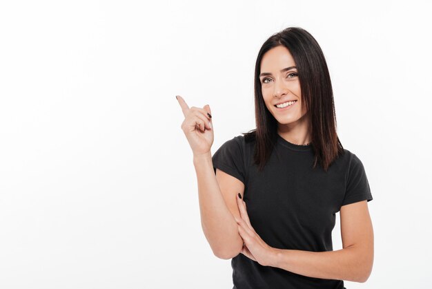 Retrato de una mujer joven feliz señalando con el dedo