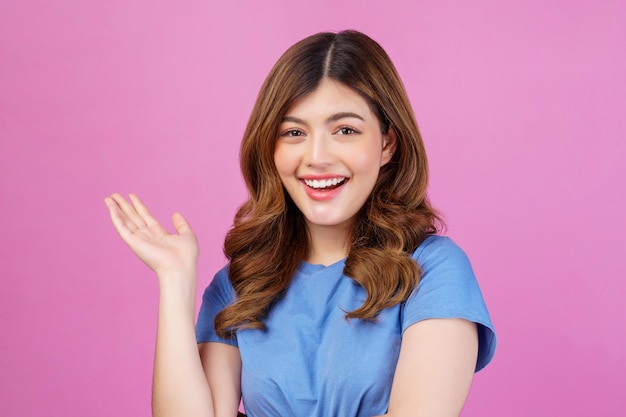 Retrato de mujer joven feliz vistiendo camiseta casual agitando las manos aislado sobre fondo de color rosa