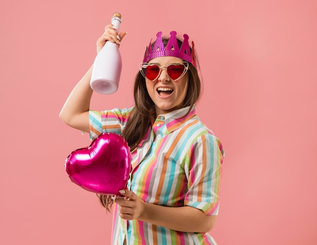 Foto gratuita retrato, mujer joven, en, fiesta, con, globo, y, botella de champaña