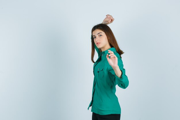 Retrato de mujer joven fingiendo tirar algo en camisa verde y mirando serio