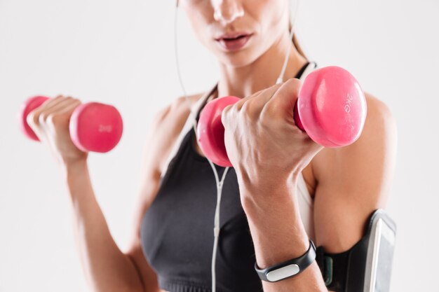 Retrato de una mujer joven fitness haciendo ejercicios con pesas