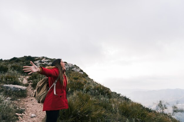 Retrato de una mujer joven en forma exaltada que está de pie en la montaña con el brazo extendido