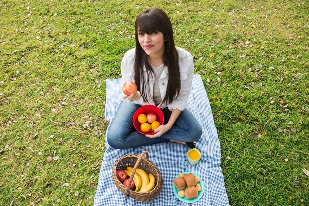 Retrato de mujer joven con frutas frescas en el parque