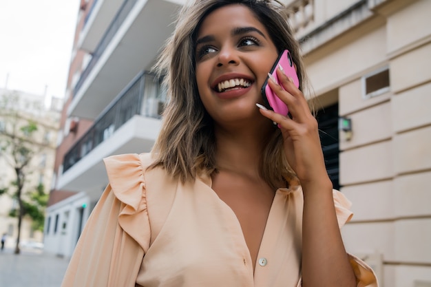 Retrato de mujer joven hablando por teléfono mientras está de pie al aire libre en la calle