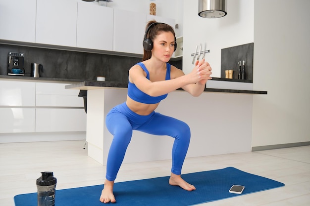 Foto gratuita retrato de una mujer joven haciendo ejercicios aeróbicos en el salón entrenamiento deportivo en casa de pie