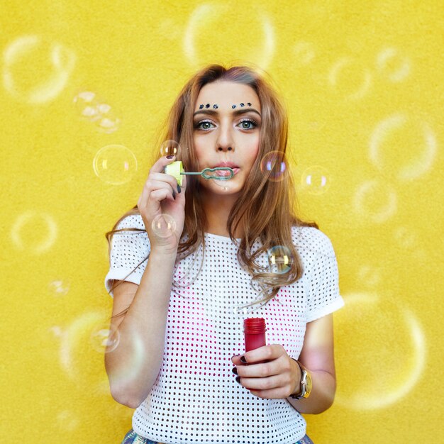 Retrato de mujer joven haciendo pompas de jabón