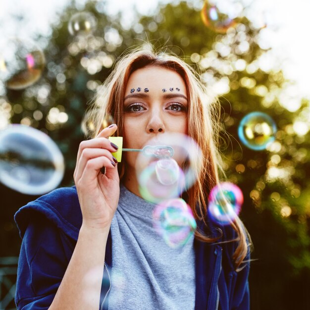 Retrato de mujer joven haciendo pompas de jabón