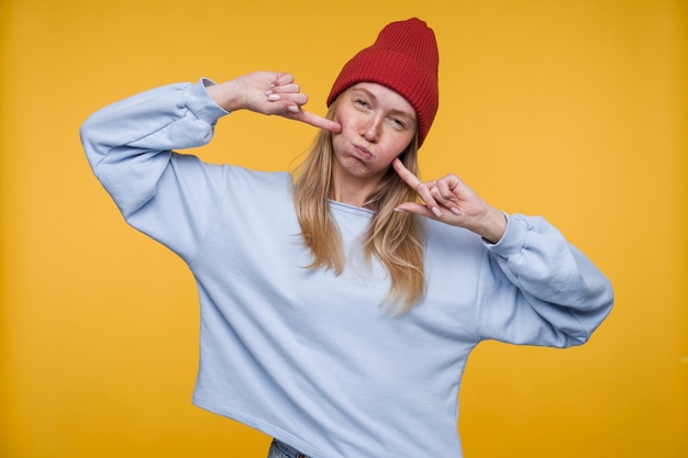 Foto gratuita retrato de una mujer joven haciendo el tonto mientras hincha sus mejillas