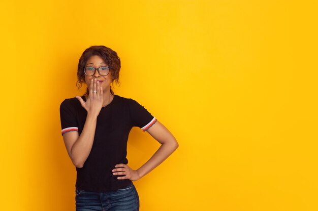 Retrato de mujer joven hermosa afroamericana sobre fondo amarillo estudio, emocional