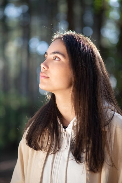 Retrato de mujer joven hermosa en el bosque. Mujer caucásica con cabello oscuro y ojos verdes mirando hacia arriba. Retrato, naturaleza, concepto de belleza.