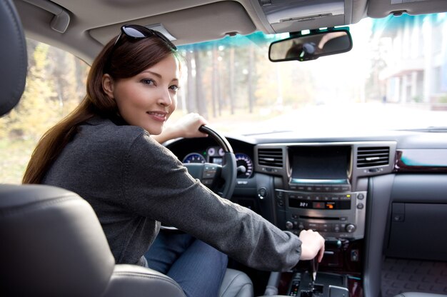 Retrato de mujer joven hermosa en el coche nuevo