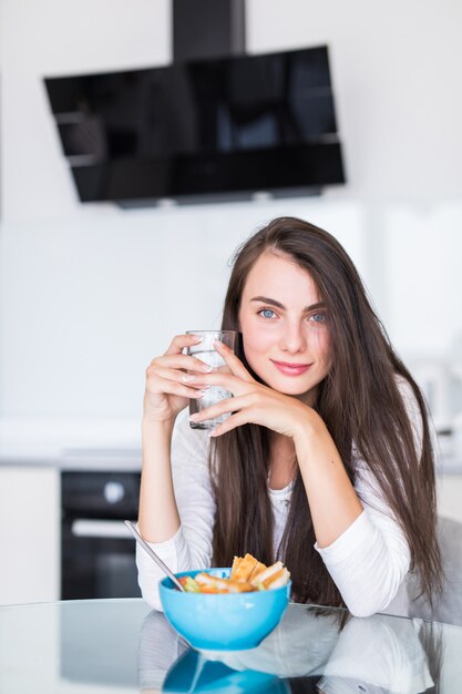 Retrato de mujer joven hermosa desayunando en la cocina.