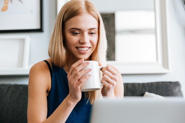 Retrato de mujer joven hermosa feliz bebiendo café en casa