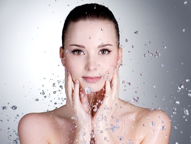 Retrato de mujer joven hermosa con gotas de agua alrededor de su rostro