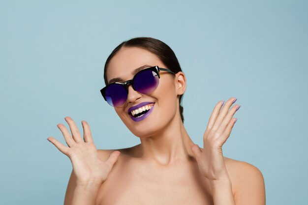 Retrato de mujer joven hermosa con maquillaje brillante aislado en la pared azul