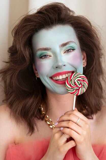 Retrato de mujer joven hermosa con maquillaje de cara colorido y piruleta