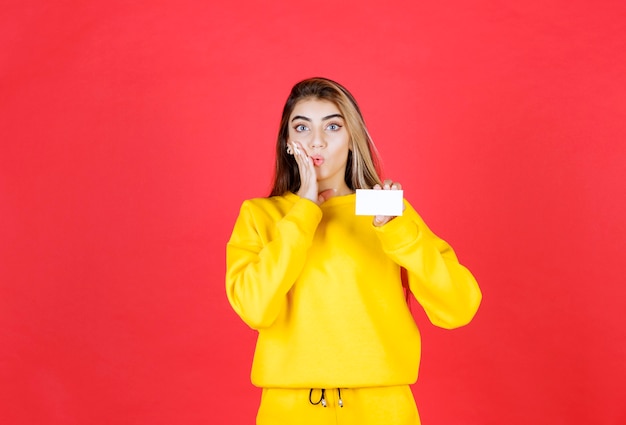 Retrato de mujer joven hermosa que muestra la tarjeta de visita en blanco