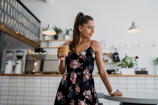 Retrato de mujer joven hermosa que va a tomar café en la mañana