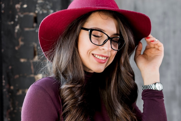 Retrato de una mujer joven hermosa sonriente con el sombrero rosado y las lentes negras