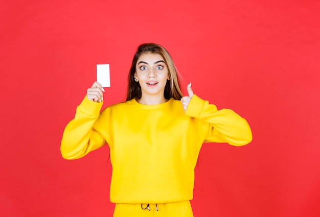 Foto gratuita retrato de mujer joven hermosa con tarjeta de presentación en blanco dando pulgares