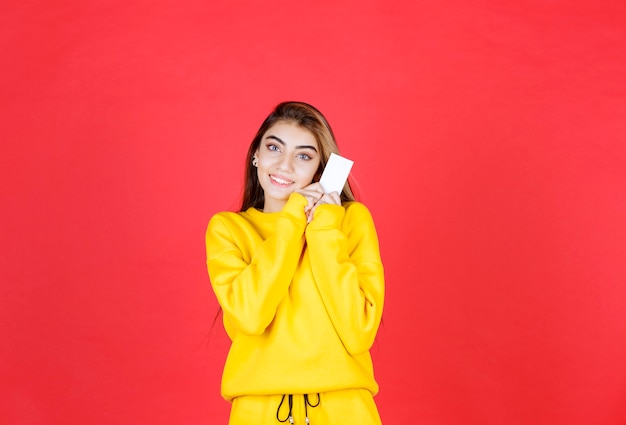 Foto gratuita retrato de mujer joven hermosa con tarjeta de visita en blanco de pie y posando