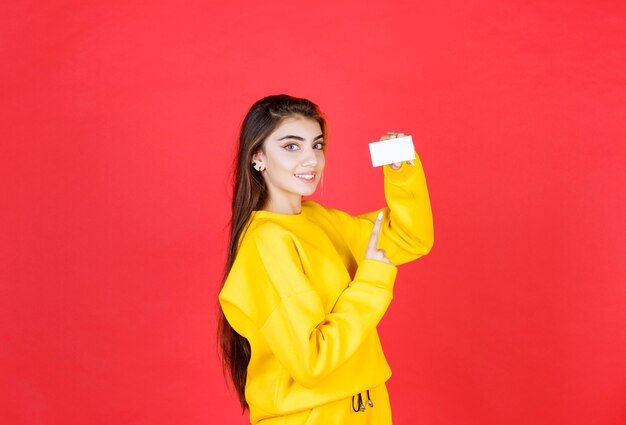 Retrato de mujer joven hermosa con tarjeta de visita en blanco de pie y posando