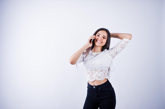 Retrato de una mujer joven y hermosa con top blanco y pantalones negros usando su teléfono