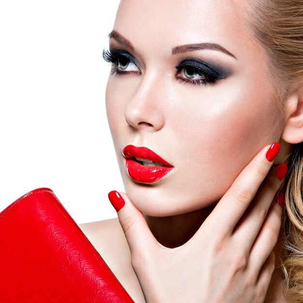Retrato de mujer joven hermosa con uñas y labios rojos brillantes. Concepto - maquillaje de moda glamour
