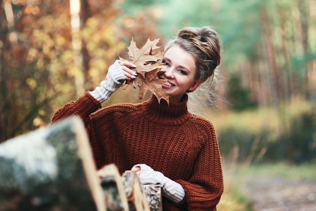 Retrato de mujer joven con hojas otoñales en el bosque