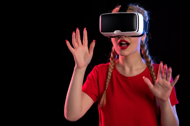 Retrato de mujer joven jugando realidad virtual en la pared oscura