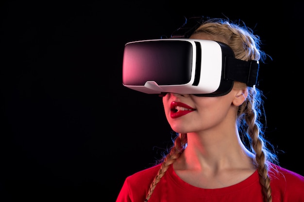 Retrato de mujer joven jugando realidad virtual en la pared oscura