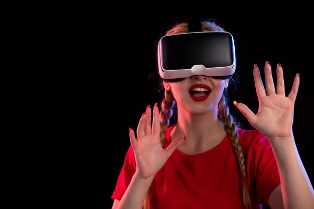 Retrato de mujer joven jugando realidad virtual en la pared oscura