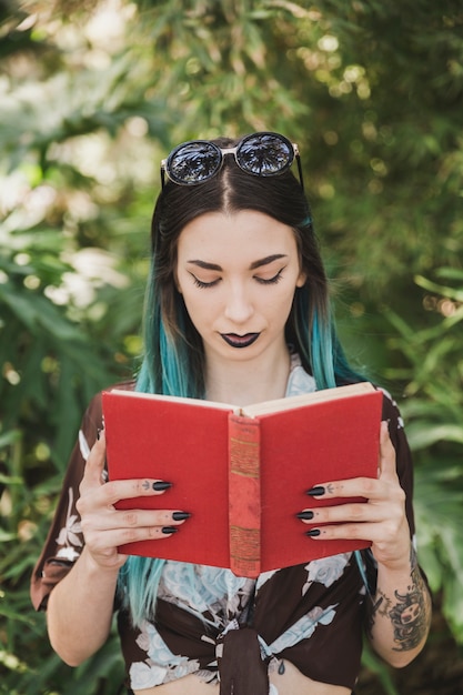Foto gratuita retrato de una mujer joven con lentes en el libro de lectura de la cabeza