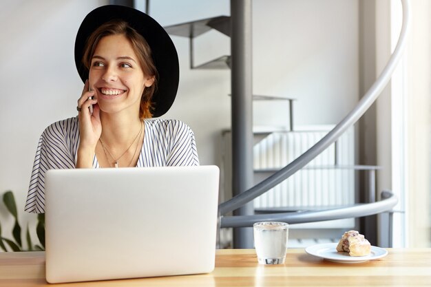 Retrato, de, mujer joven, llevando, sombrero grande, y, utilizar la computadora portátil