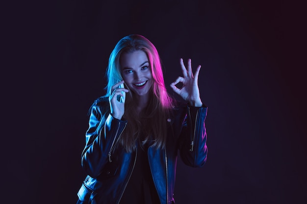 Retrato de mujer joven en luz de neón sobre fondo oscuro.